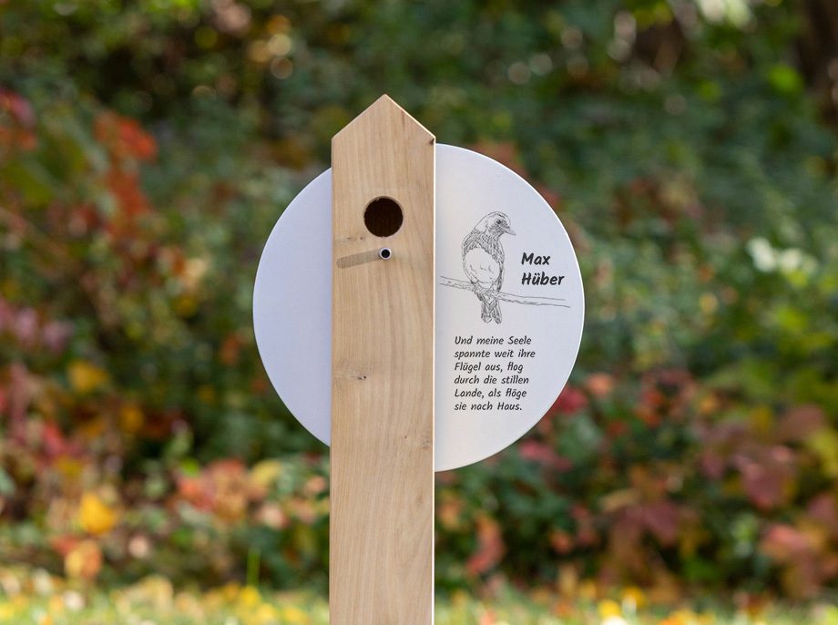 Vogelhaus-Holzgrabstele SD2.ER32 mit einem mit Vogelzeichnung und Trauerspruch gestalteten Grabschild